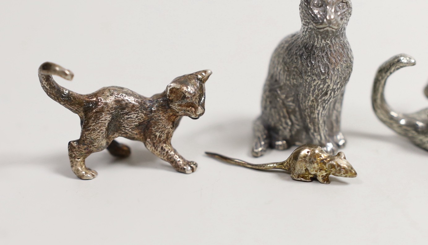 A modern silver miniature free standing model of a cat, with raised paw, London, 1995, length 37mm, together with four other base metal cats and a mouse and a cork stopper with cat finial.